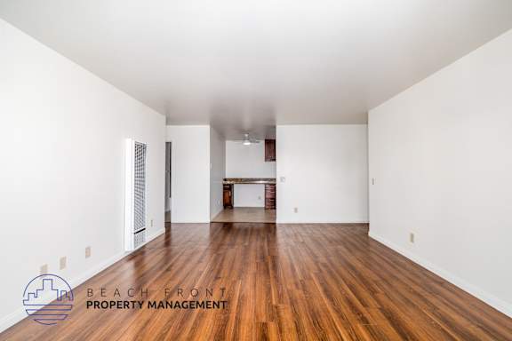 A spacious room with wooden floors and white walls.
