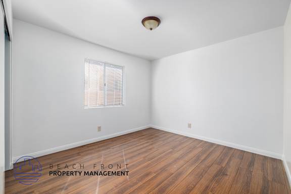 A room with wooden flooring and a window with blinds.