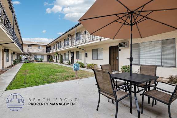 A patio with a table and chairs is shown with the logo of Beach Front Property Management.