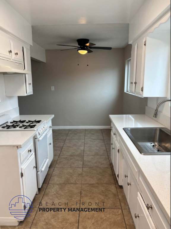 A kitchen with white cabinets and a tile floor.
