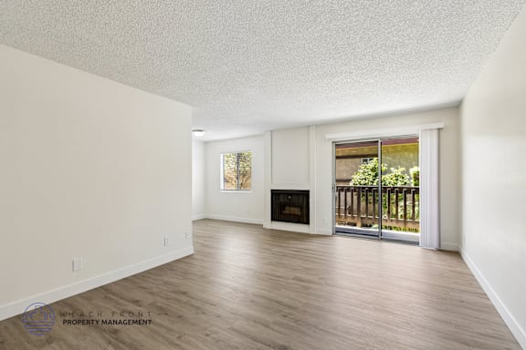 A spacious living room with a fireplace and sliding glass doors leading to a balcony.