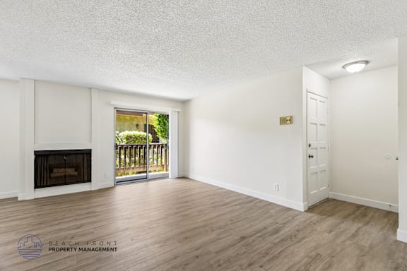 A spacious room with a fireplace and sliding glass doors leading to a balcony.