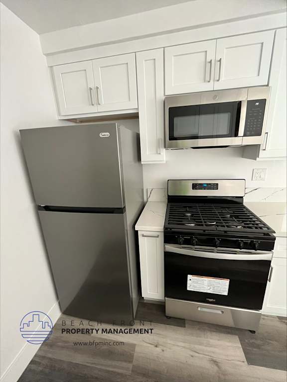 A kitchen with a stainless steel refrigerator, microwave, and stove.