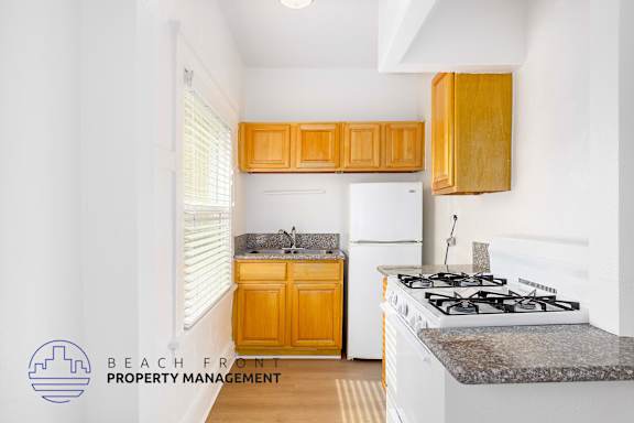 A kitchen with a stove, sink, and cabinets.