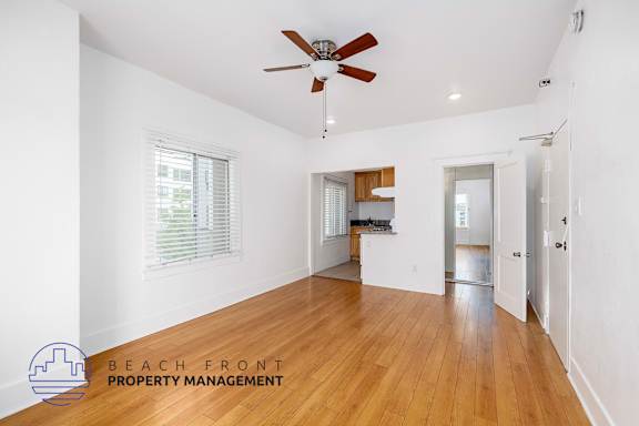 A spacious room with wooden floors and a ceiling fan.