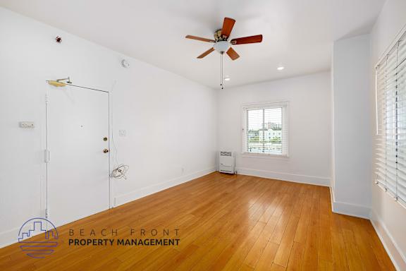 A room with a ceiling fan and wooden floors.