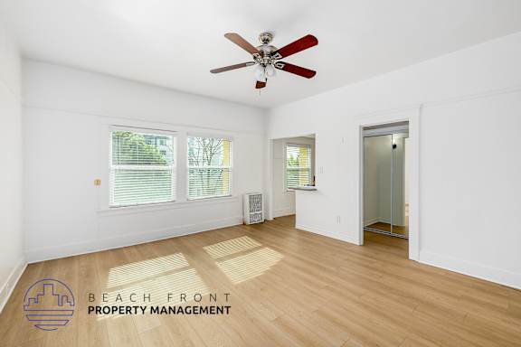 A room with a ceiling fan and wooden flooring.