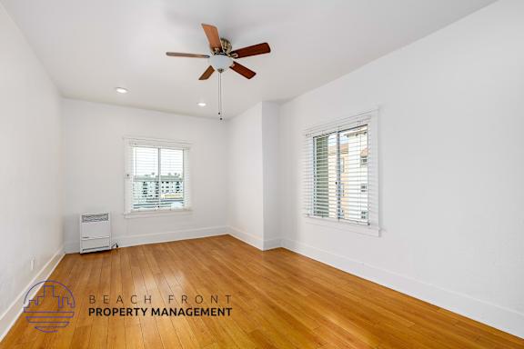 A room with a ceiling fan and wooden flooring.