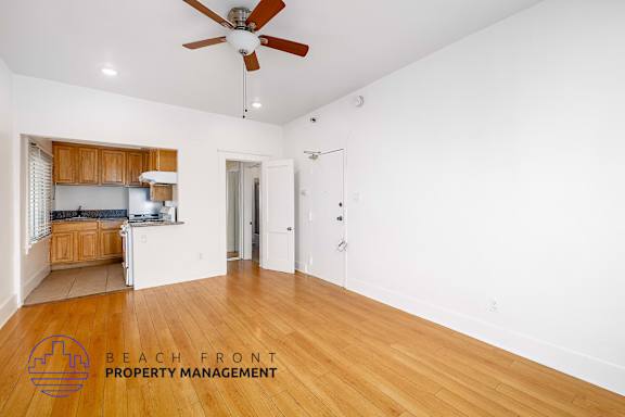 A spacious room with a ceiling fan and wooden flooring.