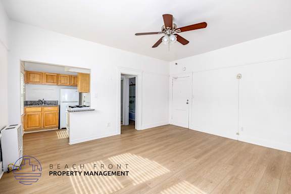 A spacious room with a ceiling fan and wooden flooring, managed by Beach Front Property Management.