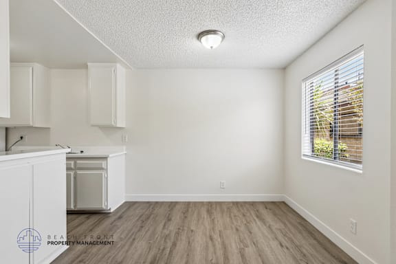 A kitchen with white cabinets and a wooden floor.