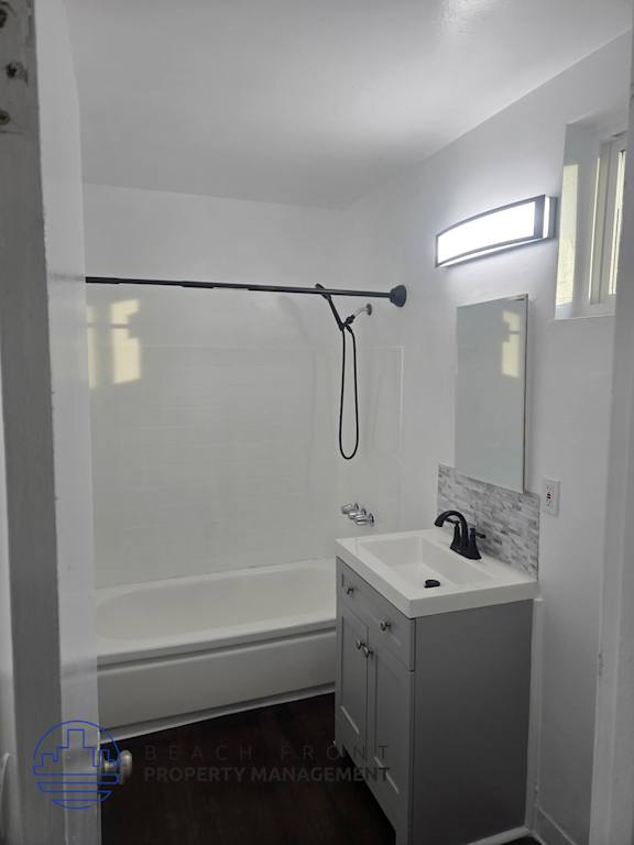 A white bathroom with a sink, mirror, and shower.