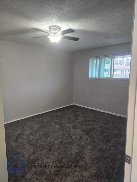 A room with a ceiling fan and carpeted floor.
