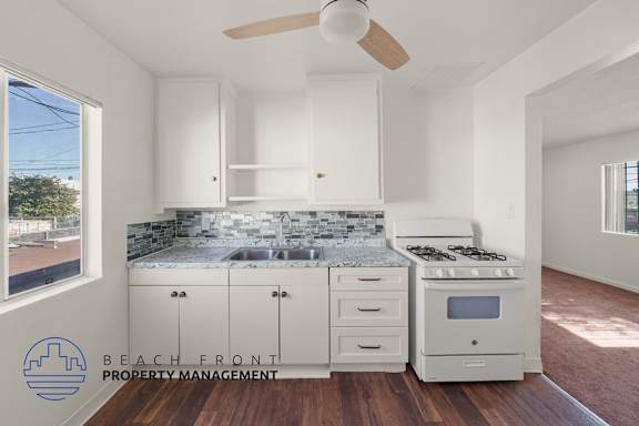 A kitchen with white cabinets and a marble countertop.