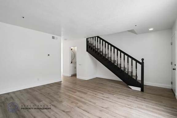 A spacious room with a wooden staircase and white walls.