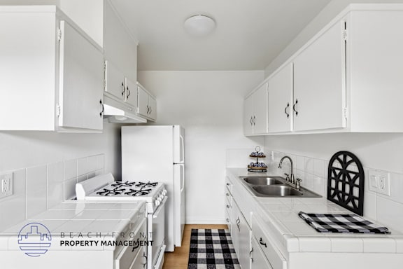 A kitchen with white cabinets and a black and white checkered mat on the counter.