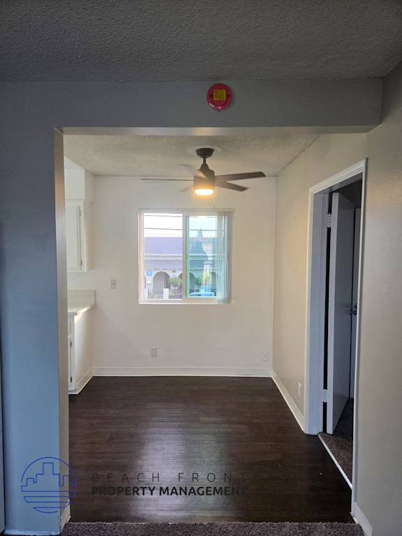 A room with a ceiling fan and a window with a view of the outside.