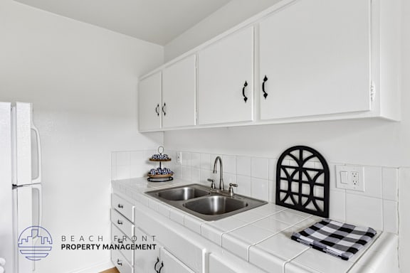 A kitchen with white cabinets and a checkered towel on the counter.