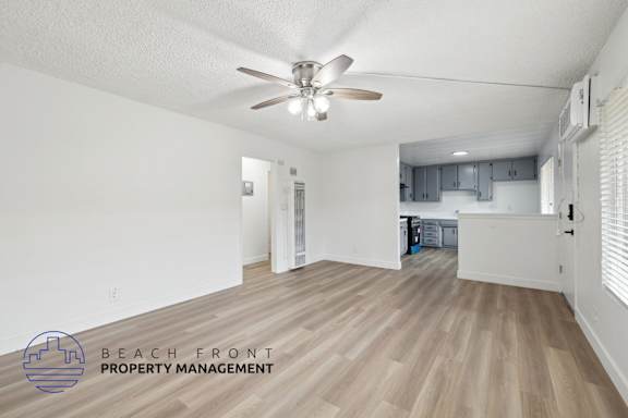 A spacious room with a ceiling fan and wooden flooring.