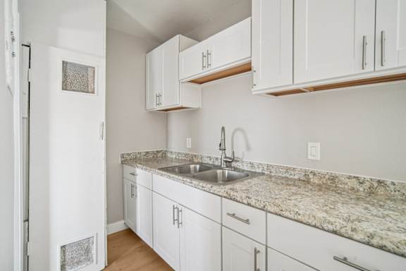 A kitchen with white cabinets and a granite countertop.