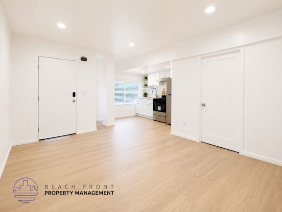 A spacious room with white doors and wooden flooring.