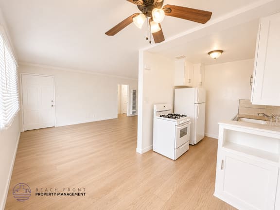 A kitchen with a fan and wooden floors.