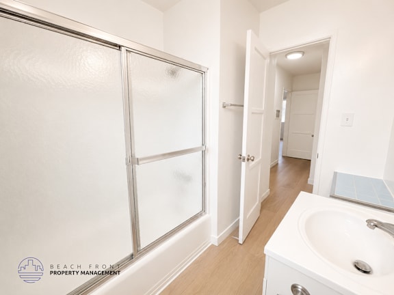 A white bathroom with a sink, mirror, and shower.