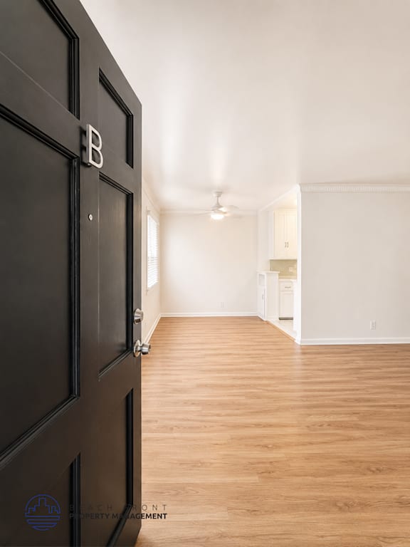 A room with a black door and wooden flooring.