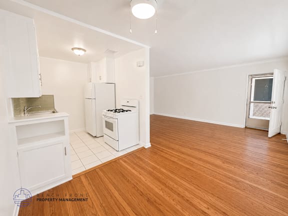 A kitchen with white appliances and wooden floors.
