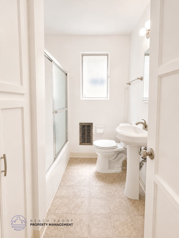 A white bathroom with a toilet, sink, and shower.