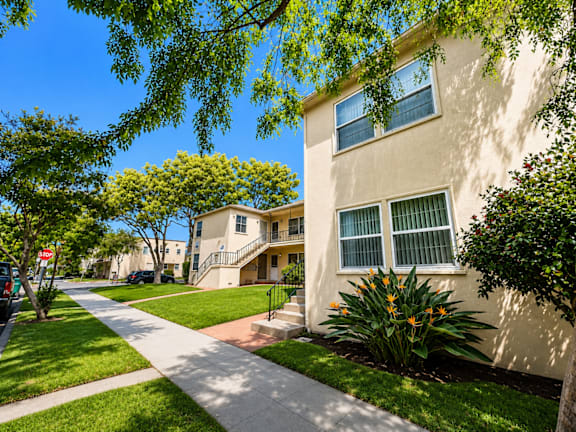 A sunny day in a quiet residential street with apartment buildings on either side.