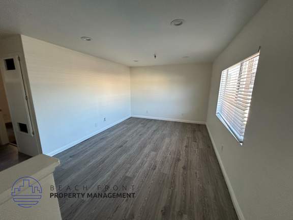 A room with wooden flooring and a window with blinds.