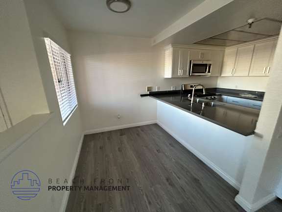 A kitchen with a black countertop and wooden flooring.