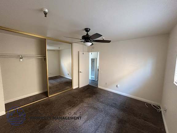 A room with a ceiling fan and a carpeted floor.