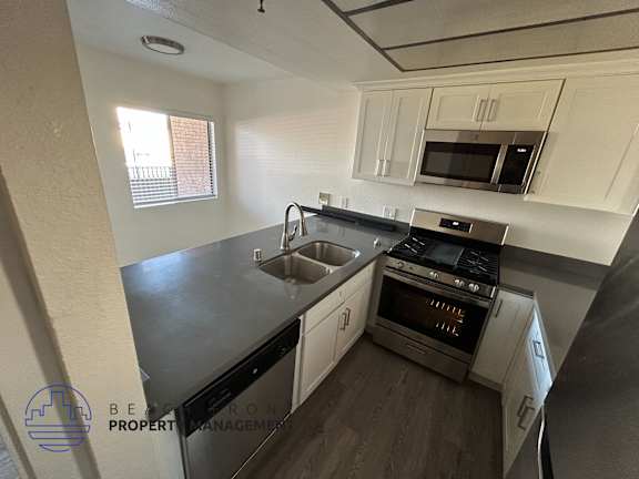 A kitchen with a stove, sink, and cabinets.