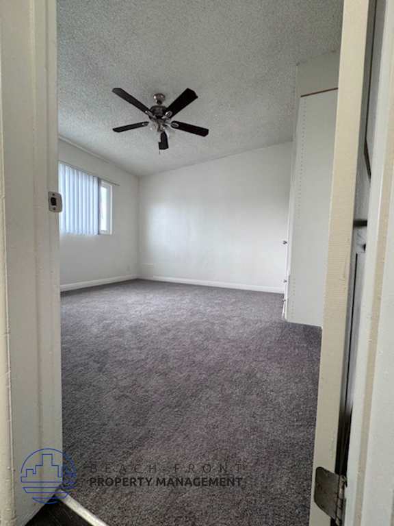 A room with a ceiling fan and carpeted floor.