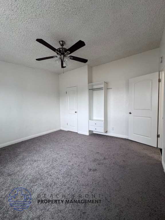 A room with a ceiling fan and carpeted floor.