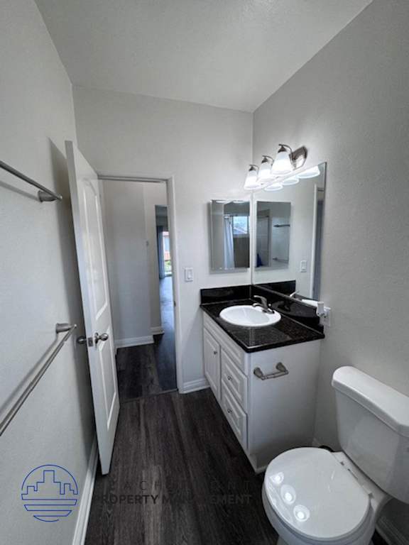 A bathroom with a toilet, sink, and mirror.
