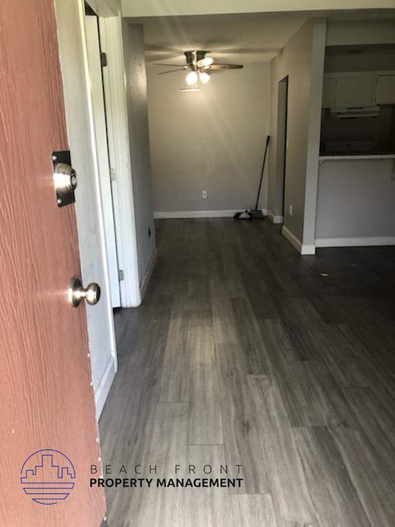 A hallway with a wooden floor and a broom in the corner.