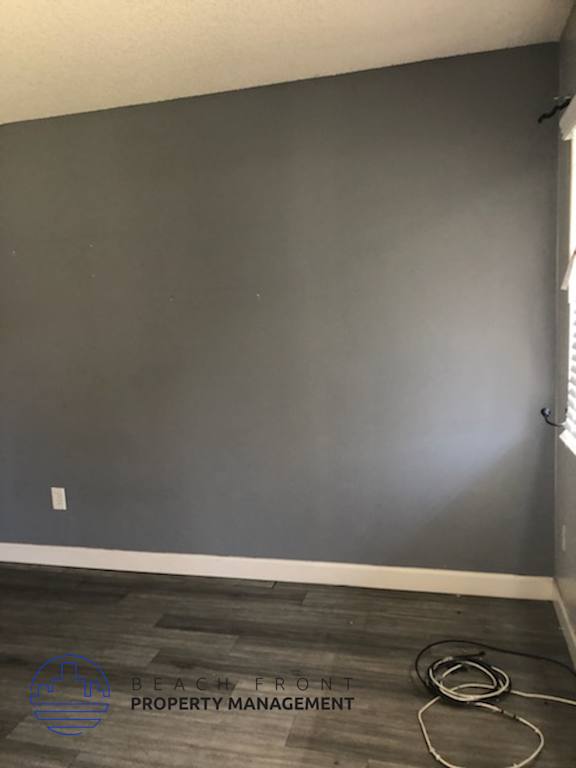 A room with a grey wall and wooden floor with a cable on it.