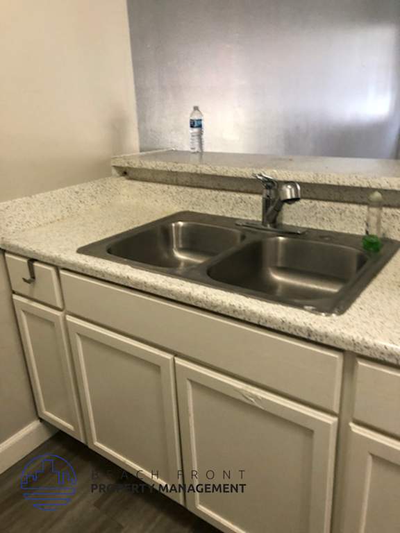 A kitchen sink with a bottle of water on the counter.