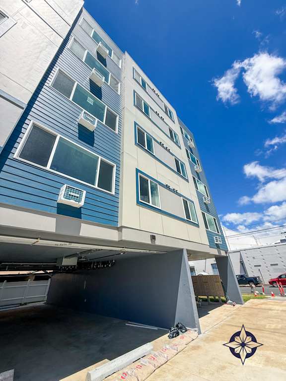A modern building with a blue and white facade and a clear sky above.