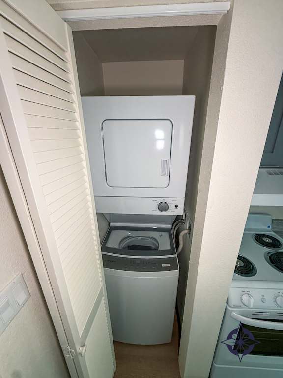 A small white fridge in a narrow space between a wall and a washing machine.
