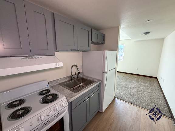 A kitchen with a white stove and a white refrigerator.