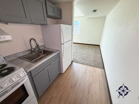 A kitchen with a stove, sink, and refrigerator.