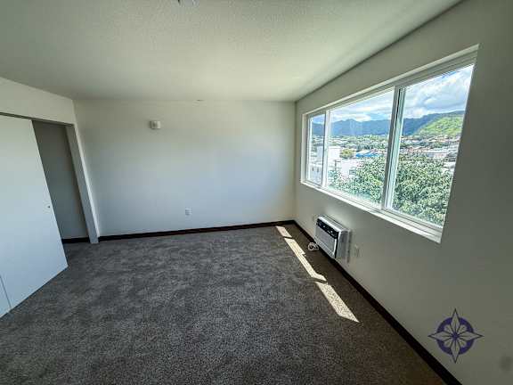 A room with a carpet floor, a window with a view of the city and mountains, and a blue star on the wall.