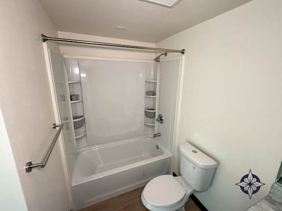 A white toilet sits next to a bathtub in a bathroom.
