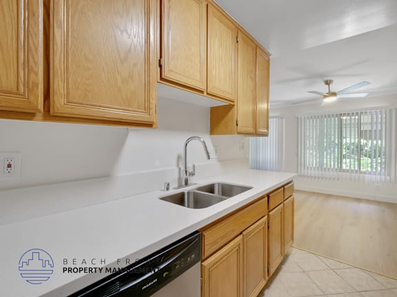 A kitchen with wooden cabinets and a black dishwasher.