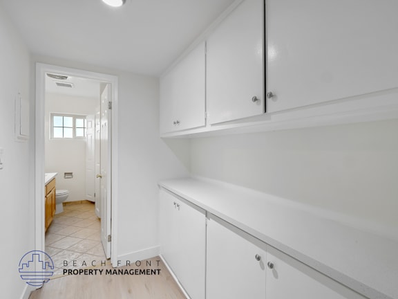 A white kitchen with a logo for Beachfront Property Management.