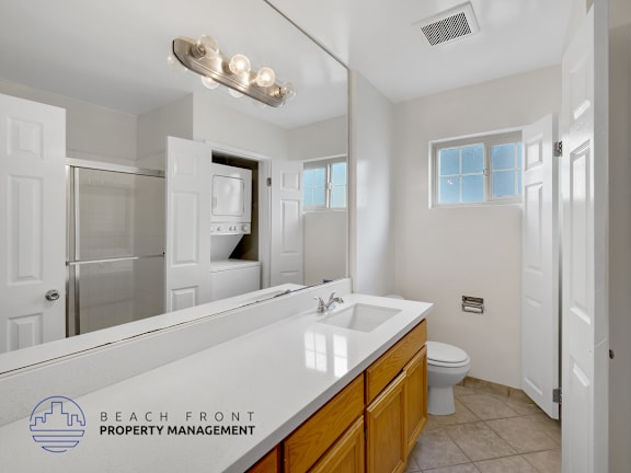 A bathroom with a sink, toilet, and mirror.